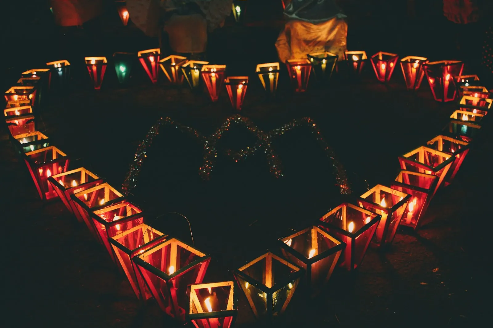 Farolitos de colores con velas encendidas colocados en el suelo formando un corazón durante la noche de los Farolitos en Ahuachapán