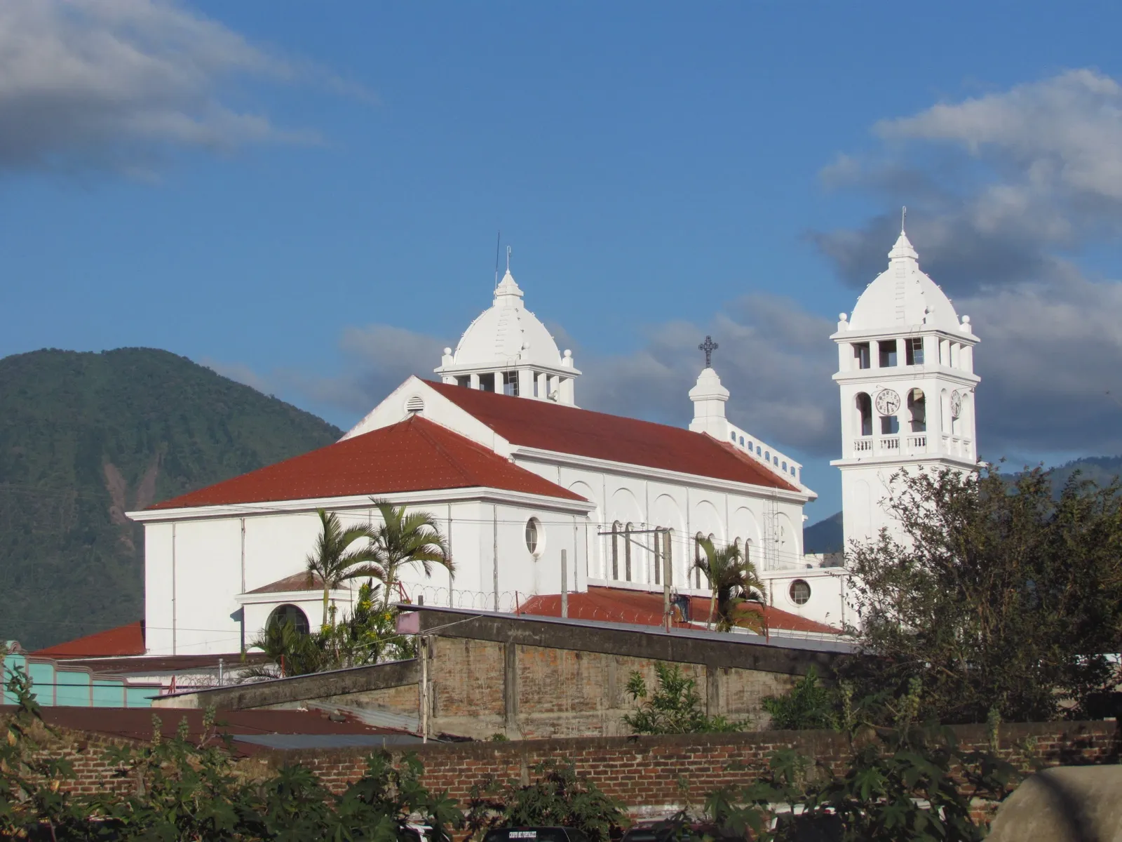 Iglesia del Cristo Negro de Juayúa, blanca con techos rojos y cúpulas, con montañas verdes de fondo