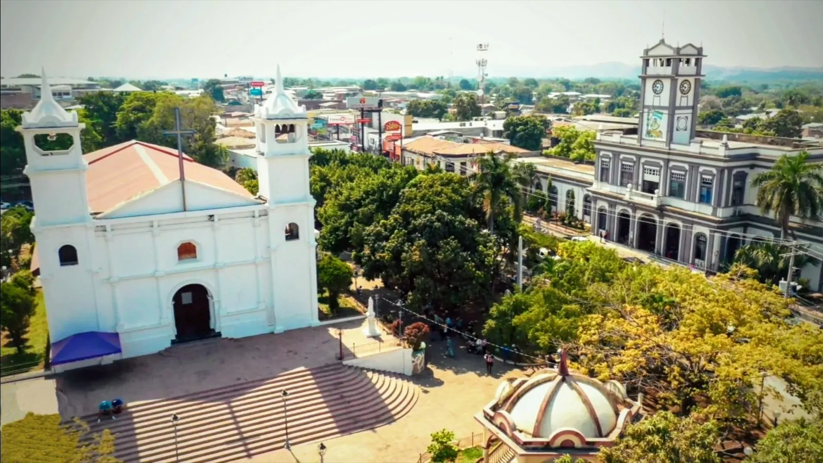 Vista elevada del parque central de Usulután con la iglesia parroquial blanca y un edificio histórico con torre de reloj